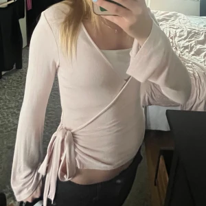 Ljusrosa omlottopp från gina tricot - Supersöt ljusrosa omlottopp från Gina Tricot i mjukt och stretchigt material💗Använd ungefär 3 gånger! Säljer för att jag knappast använder den☺️Nypris: 230 kr!