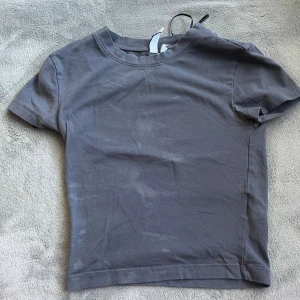 Grå basic t-shirt från H&M Divided - En enkel grå t-shirt från H&M Divided med rund halsringning och korta ärmar. Modellen är basic och passar perfekt till jeans eller kjol. Tillverkad i mjuk bomull för en bekväm känsla hela dagen.