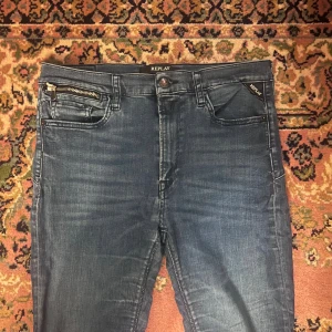 Blå Replay jeans 31/30 - Säljer ett par blå Replay Zackie jeans i klassisk tvätt med snygg dragkedjedetalj vid fickan. Jeansen har smal passform och raka ben, samt femficksdesign. Perfekta för dig som gillar stilrena och moderna jeans. Midja 39 längd 104cm (40)