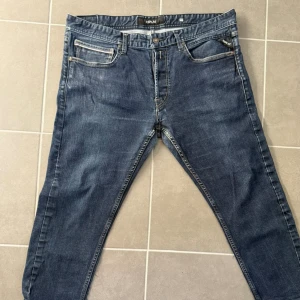 Blå jeans från Replay - Snygga blå jeans från Replay med klassisk femficksdesign och tydliga kontrastsömmar. Jeansen har normal passform och raka ben, tillverkade i slitstarkt denimtyg. Perfekta för en avslappnad och trendig look. Storlek 36x22