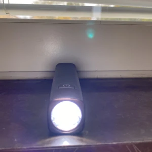 Portabel LED-ficklampa med USB-laddning - Kraftfull LED-ficklampa i svart, med USB och micro-USB-port för laddning. Kompakt och smidig design, perfekt för resor eller nödsituationer. Fungerar utmärkt, inga synliga skador eller slitage. Enkel att använda med tydlig strömknapp.