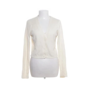 Vit ribbad kofta från H&M Divided - Säljer en  vit kofta från H&M Divided i storlek L. Koftan är ribbstickad, har v-ringning och stängs med två stora knappar framtill. Modellen är croppad och har långa ärmar, perfekt för lager-på-lager. Materialet är mjuk akryl.