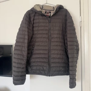 Mörkgrå Colmar jacka - Säljer en mörkgrå pufferjacka från Colmar med huva och dragkedja framtill. Jackan har quiltad design, två sidofickor med dragkedja och Colmar-logga på ärmen. Perfekt för kyliga dagar och har en clean, sportig look.