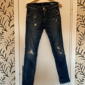 Replay Anbass  - Säljer ett par Replay Anbass jeans i storlek 28W 32L. Byxorna har slitningar där framme men och några små där back.