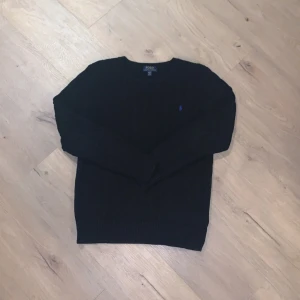 Svart stickad tröja Polo Ralph Lauren - Kabelstickad svart tröja från Polo Ralph Lauren i storlek XL. Passar storlek XS-S. Polos storlekar funkar inte likadant som vanliga storlekar. Klassisk rund halsringning och diskret broderad logga i mörkblått på bröstet. Perfekt för dig som gillar stilrena och tidlösa plagg med premiumkänsla. Det enda dåliga är att den har sytts ihop i armhålan. Det var väldigt svårt att få med på bild men det kommer inte synas när tröjan är på. Tröjan är även lite U ringad. Pris kan diskuteras vid snabb affär🚚♻️