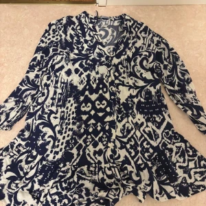 Mönstrad blåvit klänning från Zara - Säljer en snygg blåvit klänning från Zara med unikt abstrakt mönster. Klänningen har v-ringning, knappar framtill och långa ärmar. Den är luftig och har en lätt utställd form som ger en skön vibe. Perfekt för dig som gillar statement-plagg!