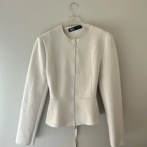 Beige kavajjacka från ZARA - Beige kavaj/jacka från Zara med dragkedja och knytband. Superfin och använd en gång!🩷