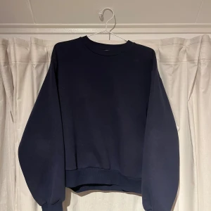 Mörkblå sweatshirt från Gina Tricot - En basic mörkblå sweatshirt från Gina Tricot, basically basics-kollektionen. Tröjan har rund hals, ribbade muddar och en loose passform med långa ärmar. Perfekt för en chill och avslappnad stil.