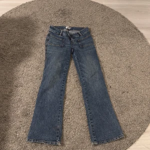 Blå bootcut jeans från 157 Paris XS - Säljer då dessa Bootcut jeans i klassisk blå tvätt från Lager 157 för att de är så för små för mig, model: Paris, storlek XS med kort benlängd. Snygga detaljer med slitna kanter vid bensluten och framfickor med markerade sömmar. Jeansen har normal passform och är tillverkade i jeansmaterial.  Ny pris: 400kr. 
