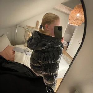 Svart glansig pufferjacka med huva - Säljer en svart, glansig och croppad pufferjacka med huva. Väldigt fin jacka, och glansig. MEN lite kort!! Så kontakta mig för mer detaljer!Kommer inte till andvändning pga väldigt kort. Perfekt skidjacka elr nåt sånt❤️