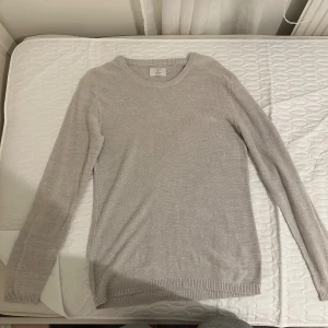 Beige stickad tröja från Emilio   - Säljer en stilren beige stickad tröja från Emilio. Tröjan har rund halsringning, lång ärm och ribbade muddar vid ärmslut och nederkant. Perfekt för lager-på-lager och enkel att matcha med jeans eller kjol.