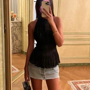 Ljusblå jeanskjol med slitna detaljer - Säljer en kort ljusblå jeanskjol med råa, fransiga kanter och slitna detaljer framtill. Kjolen har klassisk femficksdesign och knappgylf. Perfekt för dig som gillar en avslappnad och trendig stil.