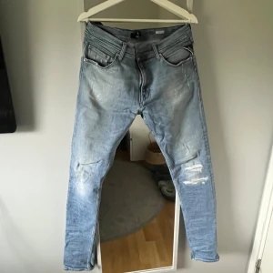 Replay ljusblå jeans med slitningar - Säljer ett par Replay ljusblå jeans med snygga slitningar och distressed detaljer på benen. Slim fit. Storlek 34/34