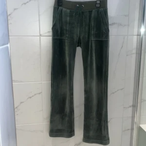 Gröna Juicy Courure  velourbyxor med snörning - Mysiga gröna byxor i velour med bred resår och snörning i midjan. Byxorna har raka ben, två stora fickor fram och en liten broderad logga på ena fickan. Perfekta för en chill och avslappnad stil.