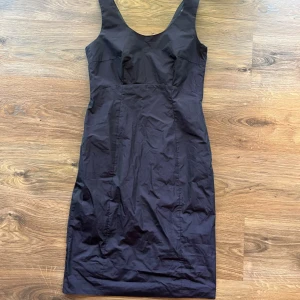 Lila skimrig klänning - Snygg lila klänning från Esprit Collection med figurnära passform och breda axelband. Klänningen är ärmlös och har en klassisk, stilren design som passar perfekt när du vill känna dig extra chic. Tillverkad i ett slätt material som ger en elegant look.