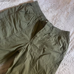Olivgröna cargo pants från BDG - Säljer ett par olivgröna cargo pants från BDG Urban Outfitters i storlek XS. Byxorna har elastisk midja, flera fickor längs benen. 