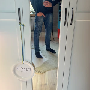 Blå slim jeans från Nudie - Snygga blå jeans från Nudie med slim passform och klassisk femficksdesign. Jeansen har en mörk tvätt med slitningar och kontrastsömmar. Tillverkade i stretchig denim för extra komfort och smidig känsla. Perfekta för dig som gillar en tajt look.