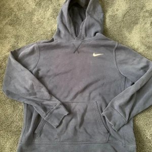 Grå hoodie från Nike XL - Säljer en grå hoodie från Nike i storlek XL. Tröjan har klassisk huva, magficka och Nike-logga broderad på bröstet. Mjuk och skön bomullsblandning, perfekt för chill eller träning. Enkel och stilren design som funkar året runt.