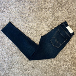 Replay anbass hyperflex  - Snygga blå jeans med en cool tvättad look. De har en slim passform och är perfekta för en avslappnad stil. Byxorna har klassisk femficksdesign och knappar i midjan. Replay anbass hyperflex jeans i bra skick. 