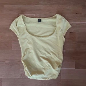 Gul topp med rund hals från SHEIN - Snygg gul topp från SHEIN med rundad, djup halsringning och korta ärmar. Enkel och fräsch design som är lätt att matcha till olika outfits. Tillverkad i mjuk bomullsmix som känns skön mot huden.
