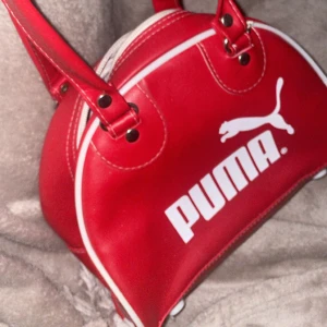 Röd PUMA-väska ä retro/vintage/y2k stil - Röd liten handväska från PUMA i retro/vintage/Y2K-modell i sportig stil. I fint skick. 