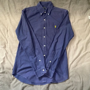 Blå skjorta Polo Ralph Lauren  - Marinblå skjorta från Ralph Lauren i storlek S. Fint skick till ett bra pris. Nypris: 1995kr. Mitt pris: 299kr                  Vid frågor eller funderingar, tveka inte att höra av dig.
