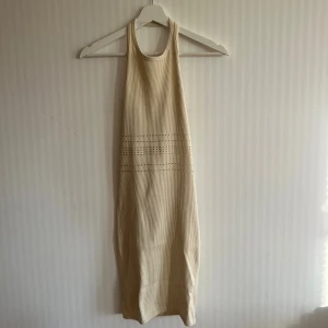 Beige seamless klänning  - Beige ribbad klänning med halterneck från Bershka. Kort seamless modell med håldetaljer i midjan. Strl S. 