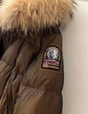 Brun Parajumpers vinterjacka m. Äkta päls - Säljer en brun pufferjacka från Parajumpers med stor fluffig äkta päls runt huvan och snyggt broderat märke på ärmen. Jackan har dragkedja, flera fickor och en klassisk vinterlook. Perfekt för kalla dagar och riktigt varm. Knappt använd, så i mycket fint skick!! En reserv lapp samt reserv knappar medföljer. (fläckarna som tillsynes finns på jackan är egentligen enbart från spegeln, alltså inte på själva jackan!) pris går att diskuteras! 🌸💞