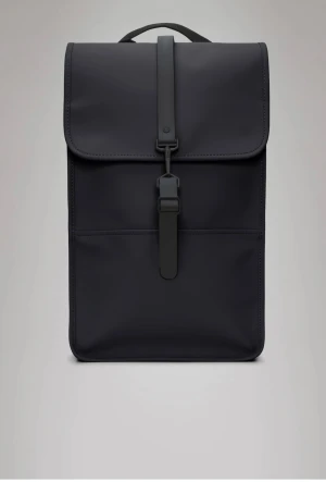 Svart ryggsäck från Rains - Snygg svart och stilren ryggsäck från Rains! Jätte smidig att ta med sig vart som helst och dessutom riktigt snygg. I väldigt bra skick då den inte är använd mycket alls.          Den här ryggsäcken har en invändig laptopficka, ett rymligt huvudfack och en dold telefonficka på bakpanelen. Laptopfickan passar en 13-tums laptop med fodral.  Backpack tillverkas i Rains vattentäta signaturtyg i PU. Nypris 1099 kr. Skriv för fler bilder!