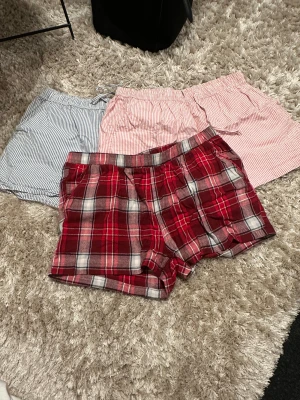 3-pack shorts randiga & rutiga - Säljer tre par shorts: ett par blåvit randiga i storlek S, ett par rödvit randiga i storlek M (båda från 157) och ett par rödvitrutiga från Esmara i storlek L. Alla har elastisk midja och är gjorda i mjuk bomull, perfekta för chill dagar eller häng hemma.