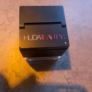 Huda Beauty Easy Bake Löspuder Pound Cake - Endast provad. Easy Bake Loose Baking & Setting Powder från Huda Beauty i nyansen Pound Cake. Löspudret kommer i en fyrkantig burk med svart lock och rosa logga. Färgen är ljusbeige och passar för att fixera smink och ge en matt finish. Innehåller 20 g puder.