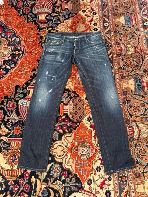 Dsquared 2 jeans 👖  - Snygga mörkblå jeans från Dsquared2 med DSQ-brodyr på bakfickan och slitna detaljer framtill. Klassisk femficksmodell med raka ben och kontrastsömmar. Jeansen har en patchad detalj på vänster lår och coolt tvättad look. Nypris runt 5599kr vid minsta funderingar så kontakta mvh CH 