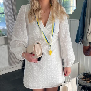 Vit studentklänning  - Superfin vit klänning från Vila. Klänningen har långa puffärmar och ett blommigt mönster. Perfekt för student och sommar! Pris kan diskuteras