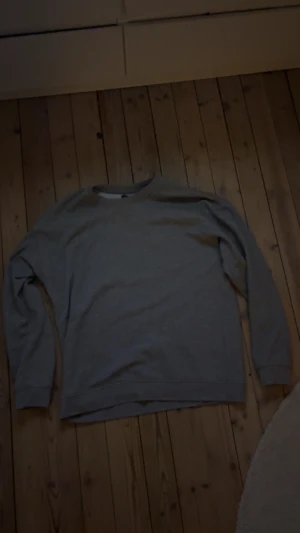 Grå sweatshirt från Jack & Jones - En skön grå sweatshirt med rund hals och långa ärmar. Tröjan har en klassisk passform och är tillverkad i mjukt material, perfekt för chill dagar men även finare tillfällen. Enkel o matcha till mycket. Tveka inte att höra av dig vid intresse eller möjliga frågor!