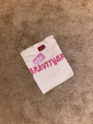 Vit Gravity Grab t-shirt med rosa tryck - Vit t-shirt från Gravity Grab med coolt rosa tryck över bröstet och rosa färgstänk på framsidan. Klassisk passform med rund hals och korta ärmar. Perfekt statement-plagg för dig som gillar streetwear och unika detaljer. Limted edition 