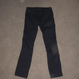 Mörkblå raka chinos  - Snygga mörkblå Chinos  från Acne med klassisk femficksdesign och raka ben. Byxorna har en enkel look med knapp och dragkedja framtill, perfekta för en clean och stilren outfit. Passar dig som gillar tidlös stil och mörka färger. 32/32 