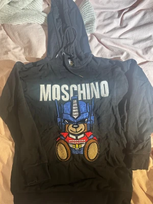 Moschino Hoodie  - Denna Moachino hoodie i begränsad upplaga har inte använts många gånger och visar inga tecken på slitage eller fläckar.