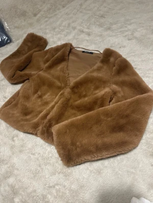 Brun pälsjacka från Gina Tricot - Säljer en fluffig och mjuk ljusbrun pälsjacka från Gina Tricot i storlek S. Jackan har långärmade ärmar, croppad passform och är helfärgad utan mönster. Perfekt för dig som vill ha en cozy vibe och gillar trendiga detaljer. 