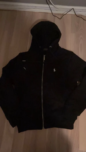 Svart Ralph Lauren zip up hoodie - Säljer min svarta Ralph Lauren zip up hoodie. Den passar men väldigt bra då jag har storlek S men den skulle även passa folk som har XS
