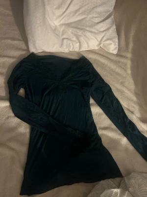 Grön långärmad topp med spets - Säljer en mörk grön långärmad topp med v-ringning från intimissimiz. Snygga spetsdetaljer längs halsringningen och vid ärmsluten. Tunn och mjuk, perfekt för dig som gillar stilrena plagg med en liten twist. Köpt för 489. Finns denna mörkgröna färg kvar längre