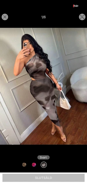 Svart asymmetrisk oneshoulder klänning - Snygg svart och gråmönstrad långklänning med asymmetrisk oneshoulder-design och cut-out vid midjan. Klänningen har figurnära passform och är tillverkad i ett tunt, lätt material som ger en cool look. Perfekt för dig som vill sticka ut med en unik stil.