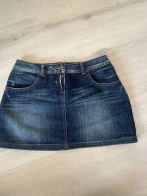 Mörkblå jeanskjol från Limited Collection - Snygg mörkblå jeanskjol från Limited Collection. Kjolen har bälteshällor, knapp och dragkedja framtill samt två bakfickor. Perfekt för dig som gillar en enkel och cool denimstil.