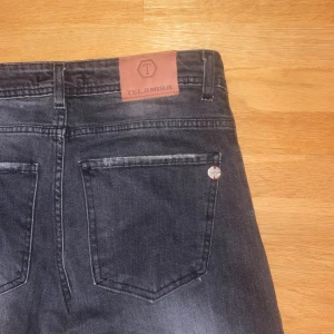Svarta jeans från Telamira - Säljer ett par svarta jeans från Telamira med snyggt slitna detaljer och klassisk femficksdesign. Jeansen har en rak passform och är tillverkade i jeansmaterial. Perfekta för dig som gillar en stilren look med lite edge. Jeansen är köpta och producerade i Italien / Rom. 