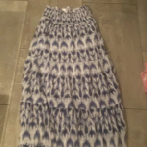 Blåvit långkjol från Gina Tricot - Säljer en långkjol från Gina Tricot i storlek 146/152. Säljs inte längre!Kjolen är blåvit med ett unikt mönster och har resår i midjan för extra komfort. Perfekt för dig som gillar en luftig och flowy stil. Använt ca 1 gång!