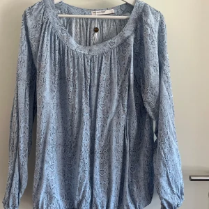 Blå blus med ormmönster - Säljer en blå blus från Soyaconcept i storlek L med ormmönster. Blusen har långärmade ärmar, rundad halsringning.  