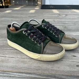 Feta Lanvins! - Snygga skor i mörkgrön mocka med svarta snören och beige sula. Tåpartiet är i blankt, brunt material som ger en cool kontrast till resten av skon. Perfekta för dig som gillar unika detaljer och stilren design.