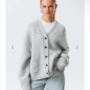 Grå oversized kofta från Weekday - Mysig grå kofta från Weekday i oversized modell med stora fickor framtill och ribbade muddar. Koftan har v-ringning, knappar hela vägen och är stickad i ett mjukt material. Perfekt att slänga på sig över en t-shirt för en chill look.