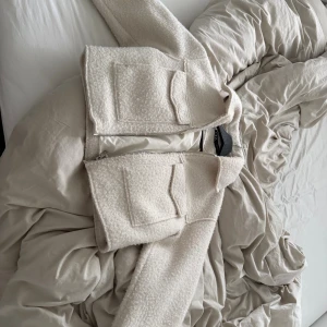 Beige teddyjacka från Zara - Säljer en beige teddyjacka från Zara med två stora fickor framtill och silvrig dragkedja. Jackan är croppad och har en mjuk, fluffig yta som ger en chill vibe. Perfekt för lager-på-lager och snygg till både jeans och kjol.
