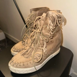 Beiga mockaboots med fransar - Unika boots i beige mocka med coola fransdetaljer och snörning framtill. 💕
