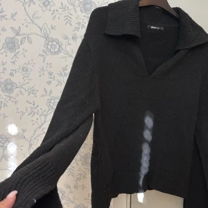 Svart stickad tröja  - Svart stickad tröja från Gina Tricot med bred krage och v-ringning. Tröjan har långa ärmar med ribbade muddar och liten slits detalj vid sidorna. Knappt använd, inga defekter 